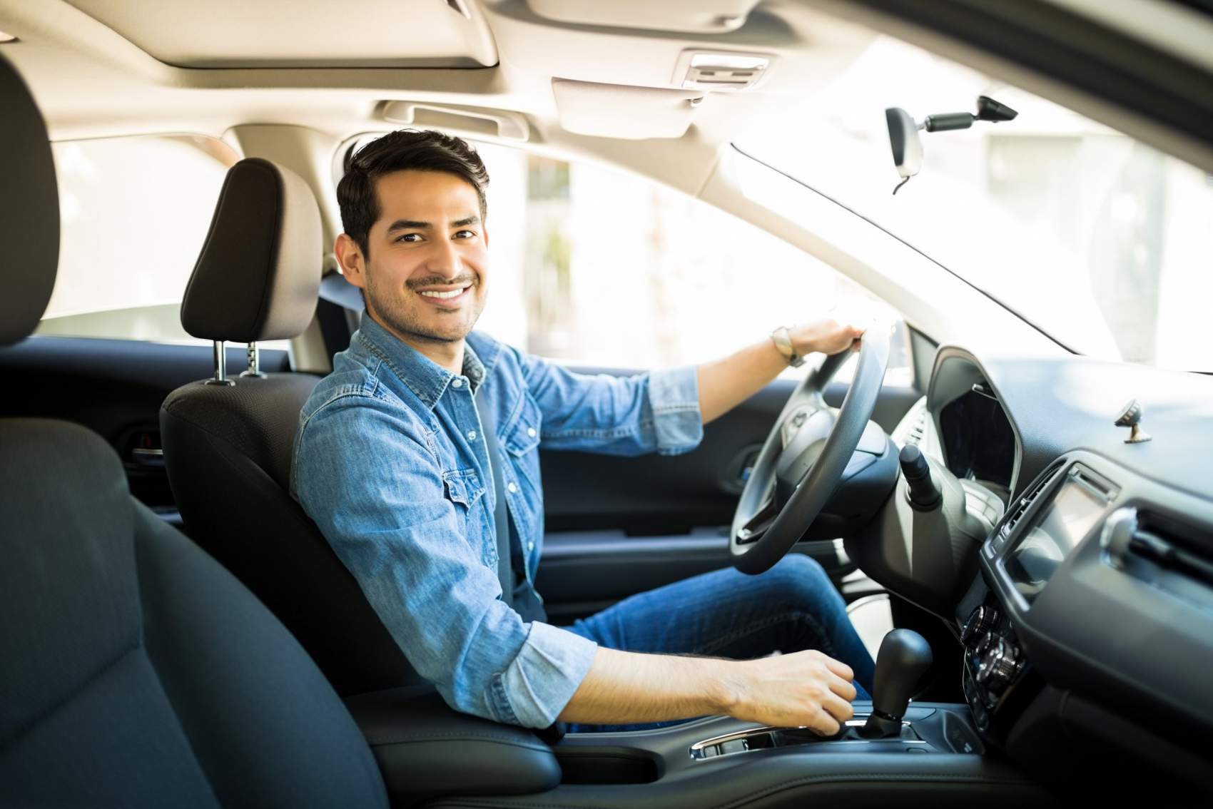 Portrait of handsome young man sitting in the driving seat of his car and making eye contact